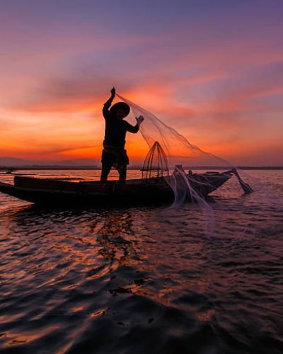 Silhouette of traditional fishermen throwing net fishing inle lake at sunrise time, Myanmar