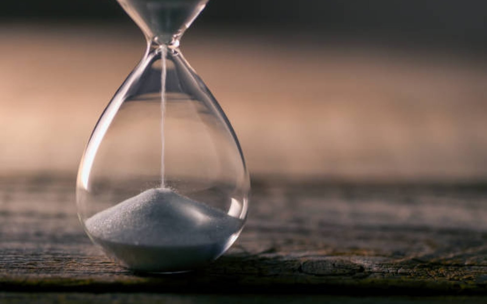 Flowing  white hourglass on wooden table; Twilight blue