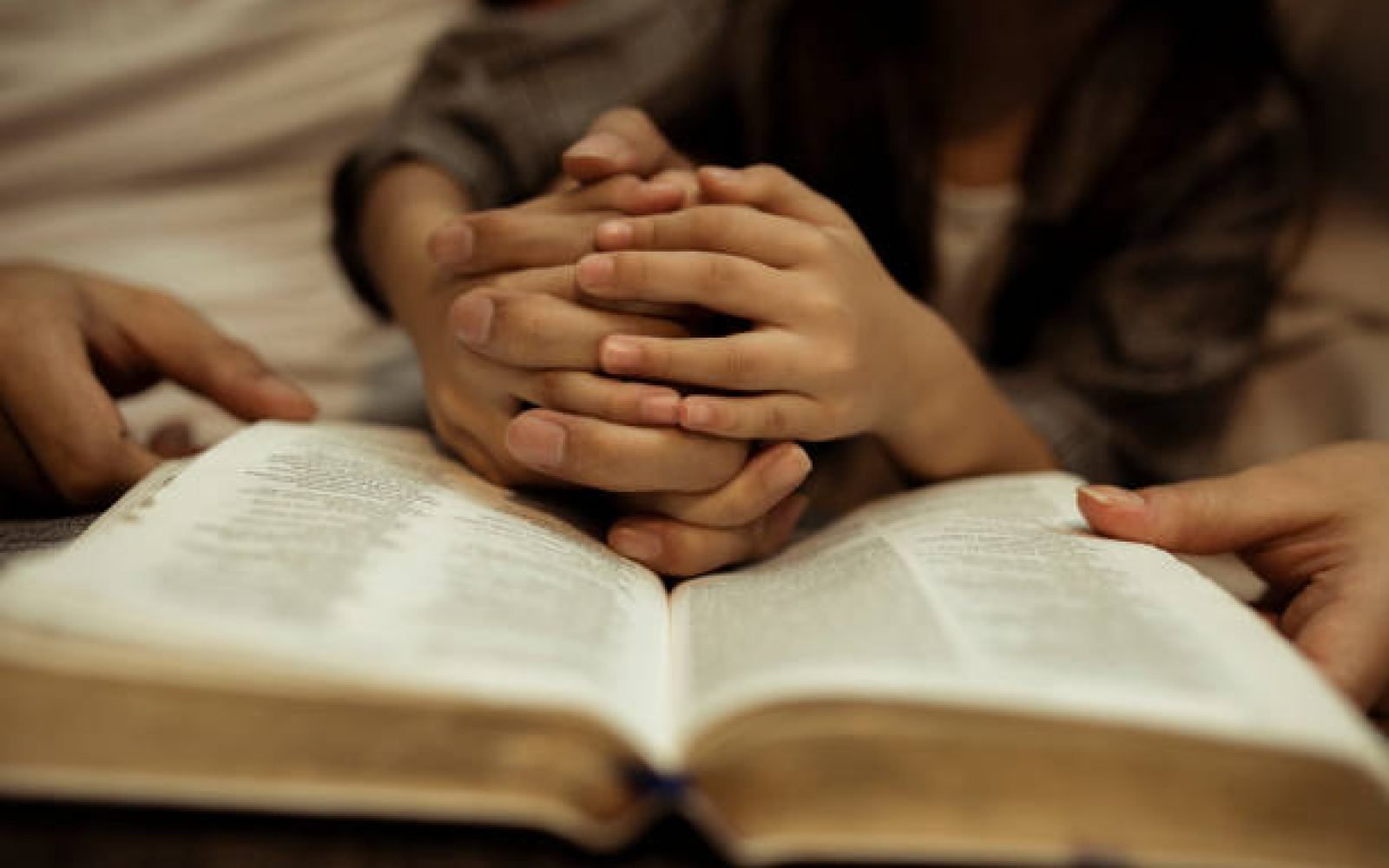 a kid reading the holy bible with guide by parents