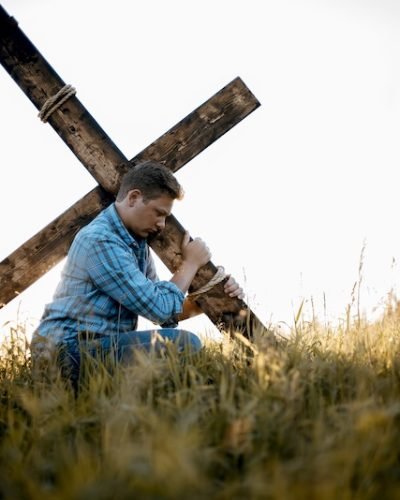 A shallow focus shot of a male carrying a handmade cross