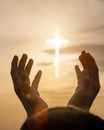 Concept of prayer and religion. Hands reach for the sky and the Cross.