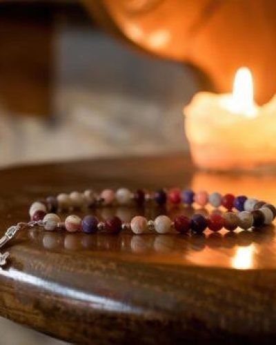 rosary-beads-and-candle-light-on-wooden-table-in-a-church-photo