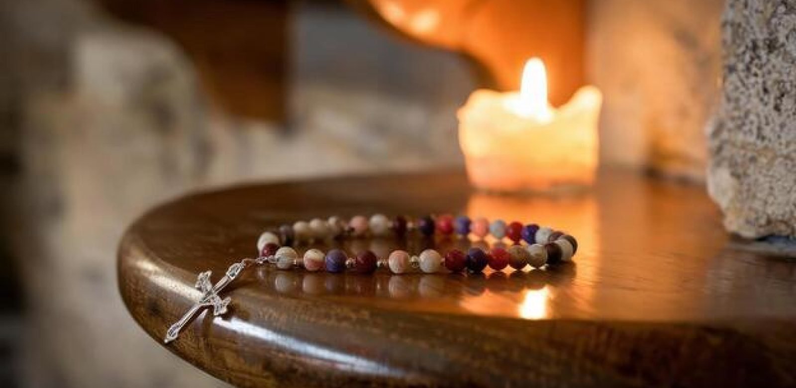 rosary-beads-and-candle-light-on-wooden-table-in-a-church-photo