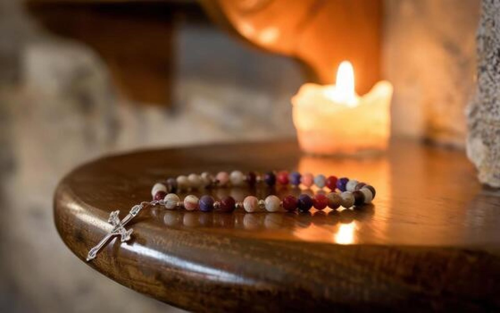 rosary-beads-and-candle-light-on-wooden-table-in-a-church-photo